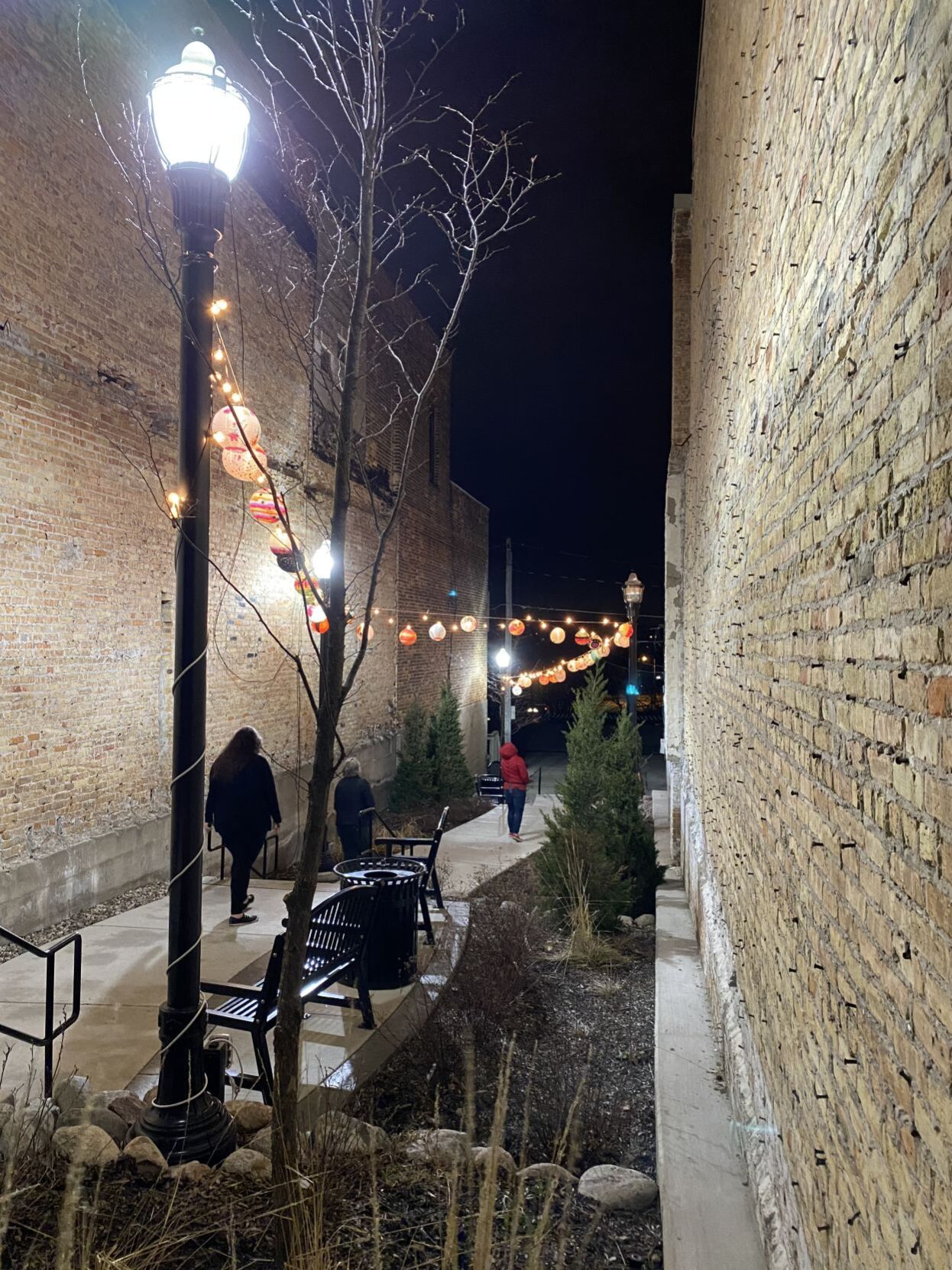 People walk underneath lanterns in Uptown